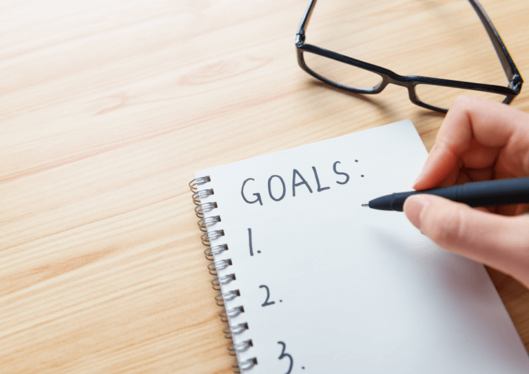 Person joyfully writing down goals for 2024 on a notepad