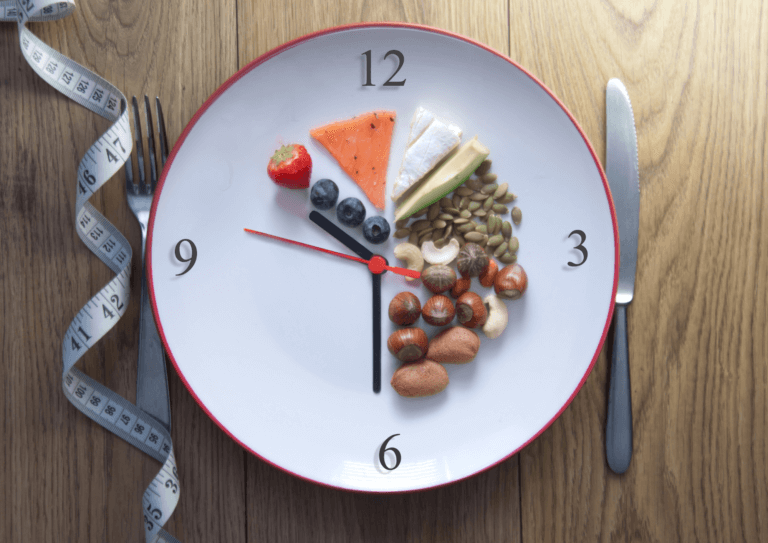 A plate with a clock on it, surrounded by a spread of nutritious food, symbolizing intermittent fasting and mindful eating.