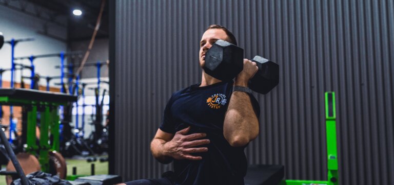 Personal trainer performing a dynamic full-body exercise, illustrating the effectiveness of comprehensive workouts for weight loss.