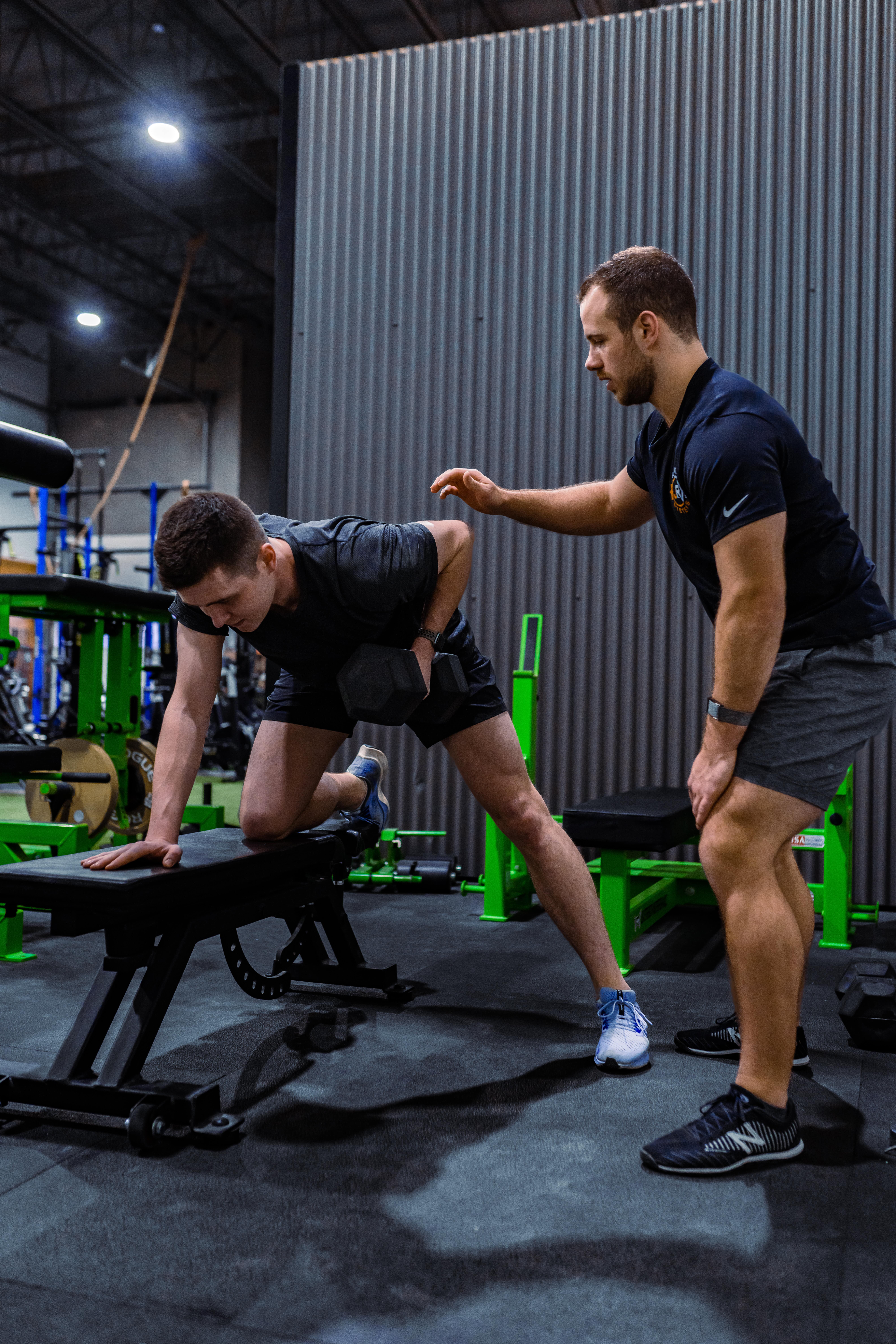 Personal trainer in Langley demonstrating one-arm dumbbell row to client for effective back strengthening